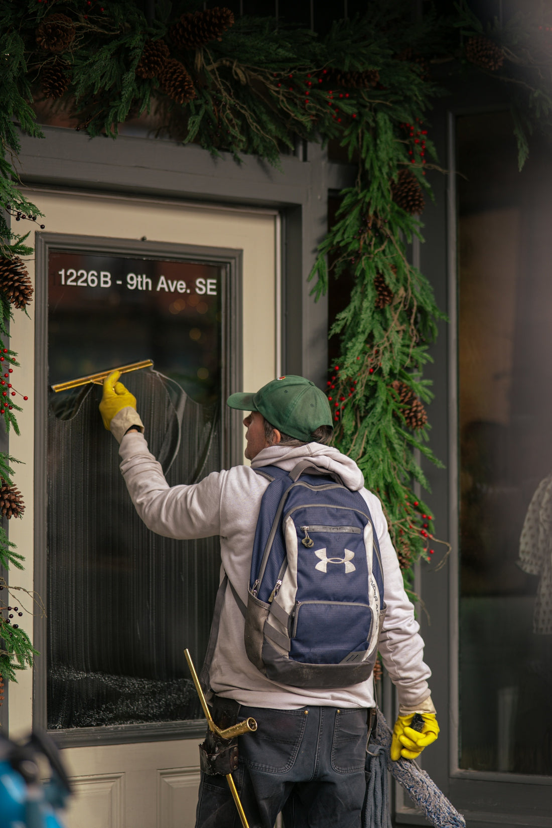 Man cleaning a storefront window with a squeegee